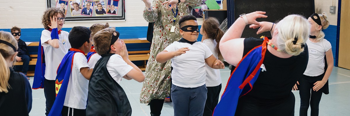 A group of school children rehearse their heroes and villains dance in their school hall with two of their teachers, all caught up in an imaginary battle between the forces of good and evil.
