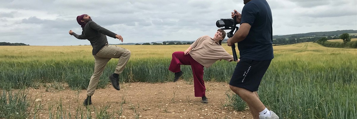 Two dancers perform in a crop field in Dorset, the site of a buried Iron Age settlement. They are filmed by a single film director with a camera, Dan Martin.